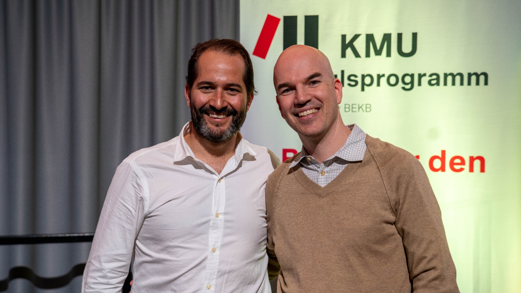 Zwei Teilnehmer vor dem KMU-Impulsprogramm-Banner