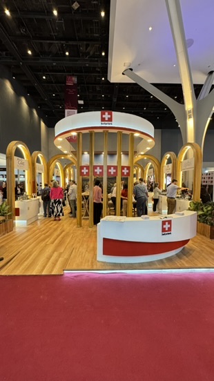 Schweizer Pavillon mit goldenen Bögen und rundem Empfangstresen an der ProWine Mumbai 2025.