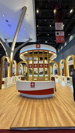 Zentraler Empfangstresen des Schweizer Pavillons mit Schweizer Flaggen.