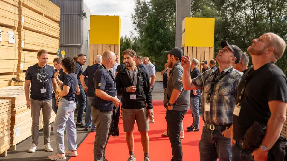 Gäste mit Namensbadges stehen auf dem roten Teppich, mehrere blicken nach oben.